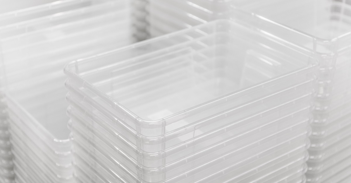 A large amount of clear plastic food containers stacked within each other. There are multiple stacks near each other.