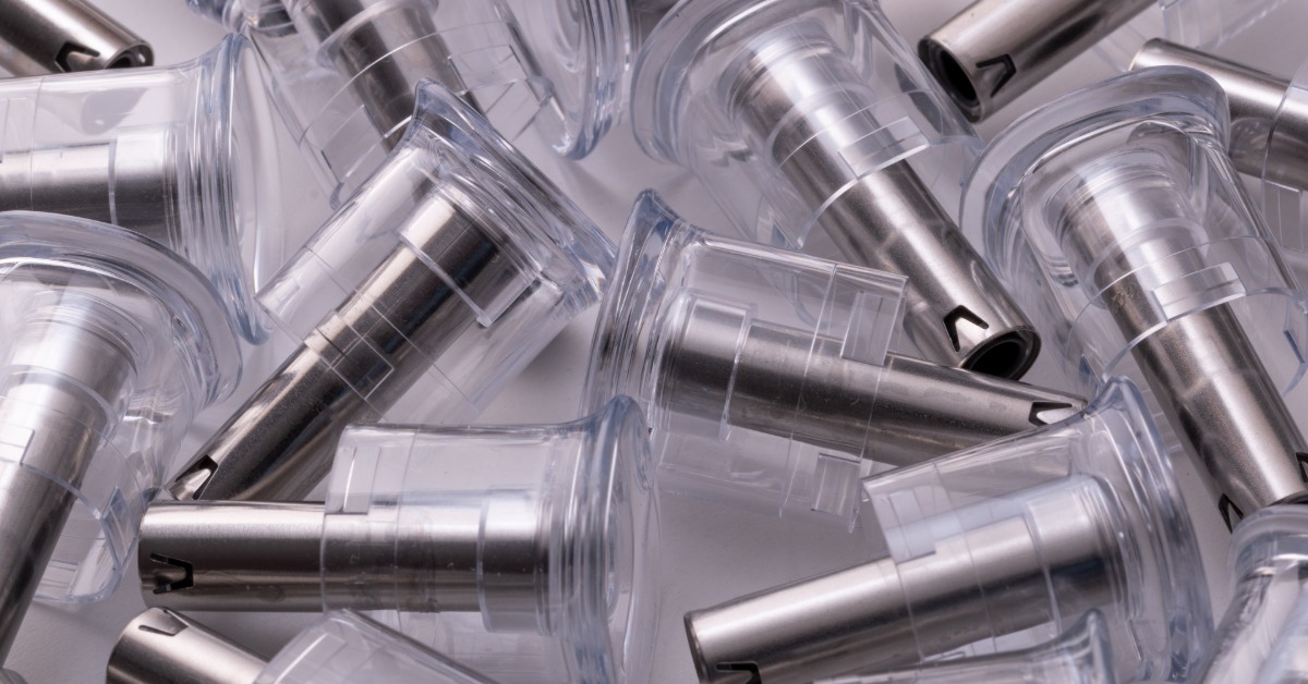 A handful of small metal tips with clear plastic caps formed using plastic injection molding processes.